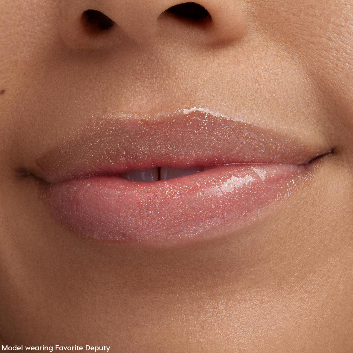 Glossy lips wearing Squad Dreams, a ColourPop Ultra Glossy Lip, shimmering with fine gold sparkle in a sheer pink wash, shown in a tight macro beauty shot under soft studio lighting on smooth skin.