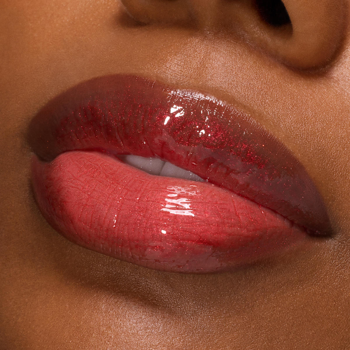 Slightly parted lips wearing ColourPop Ultra Glossy Lip in Runs with Vampires, showcasing a deep berry-red gloss with fine red shimmer and mirror shine in a macro close-up on deep skin.