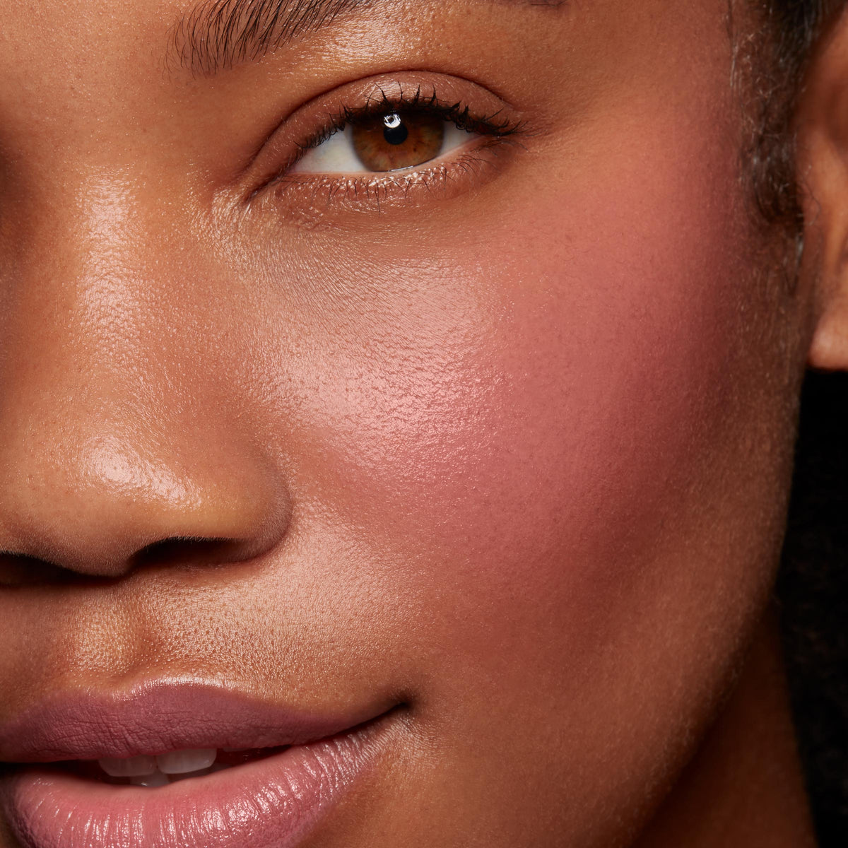 Verified ColourPop Lip and Cheek Balm delivering a dewy rosy flush on the cheek and a soft lip tint, shown in a studio close-up of a model’s face to highlight smooth, buildable color and a natural glow.