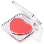 It’s a Look lip and cheek balm displayed in a half-open clear compact, revealing a heart-shaped coral pan; a creamy, buildable ColourPop Lip and Cheek Balm for multi-use tint on lips and cheeks, shown on a clean white backdrop.