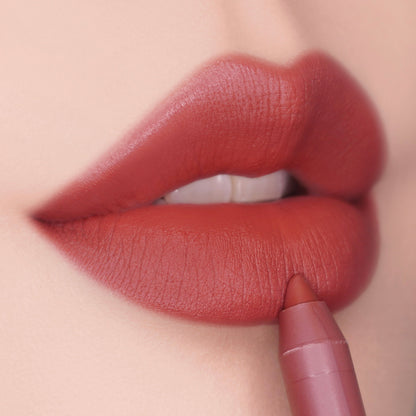 ColourPop Lippie Pencil in Love Bug defining and filling lips, delivering a rich warm terracotta-red matte finish in a close-up beauty shot, highlighting the precise tip and smooth, full-coverage application.