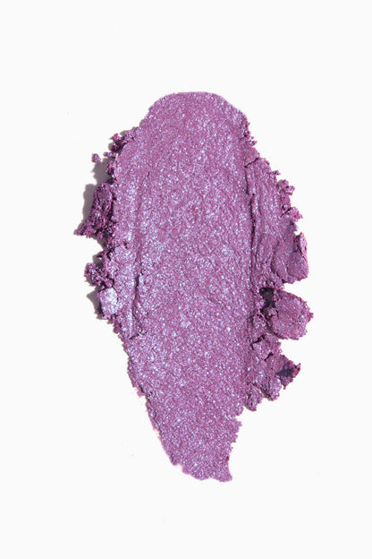 Ripple Super Shock Shadow by ColourPop swatched in a thick oval smear, a creamy lavender-purple eyeshadow with blue iridescent shimmer and metallic finish, spread on a clean white background.